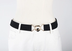 Detail of black elastic belt with gold double-ring buckle on white denim pants