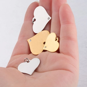 Polished stainless steel heart pendants with zircons held in hand to show 20/25mm size