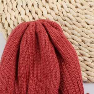 Detailed close-up of chunky knit texture on dark red winter beanie for children