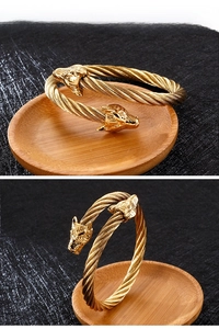 Détail macro du bracelet jonc tête de loup doré avec design en fil torsadé complexe