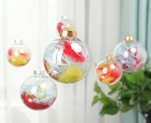 Close-up of clear Christmas ornament ball filled with colorful feathers and gold metal cap