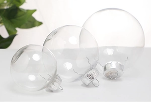 Three sizes of transparent PET Christmas baubles with silver hanging caps on a white surface