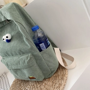 Green corduroy backpack with cartoon eyes and side pocket for water bottle