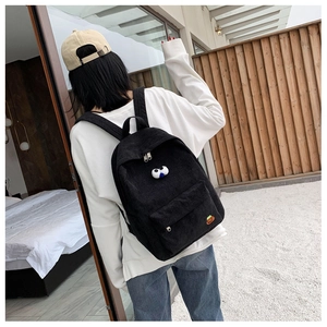 Detail of black corduroy backpack with cute cartoon eyes decoration and front pocket