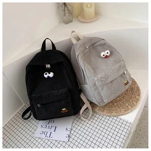 Detail of black and grey corduroy backpacks with cartoon eyes on a lifestyle background