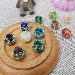 Leuchtende Goldsand-Glasperlen für DIY-Schmuck auf Holzsockel und Leinenstoff