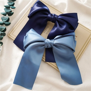 Close-up of elegant satin bow hair clips in navy and grey-blue with long ribbon tassels