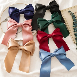 Elegant satin bow hair clips with long ribbons in multiple colors on white fabric