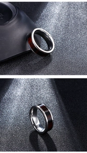 Macro detail of the silver stainless steel ring featuring a deep red wood inlay texture