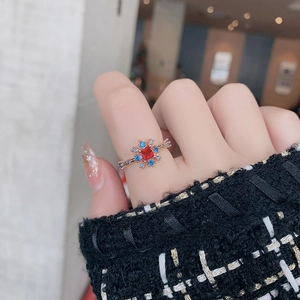 Detailed view of a rose gold snowflake ring with square red stone and blue zircon accents