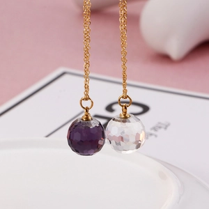 Macro shot of faceted crystal sphere drops in purple and clear on elegant gold chain