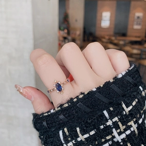 Detail of rose gold flower ring with marquise-cut navy blue stone worn by a model
