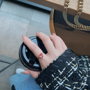 Detail of rose gold open ring featuring a pink heart stone and a sparkling pendant charm