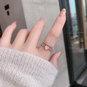 Close-up of rose gold ring set with pink heart stone and colorful crystal flower details