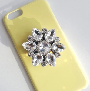 Detail of flower-shaped crystal rhinestone phone grip on light yellow hardshell case