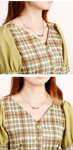 Gros plan d'un collier en or rose avec trois pendentifs en trèfle porté par un mannequin