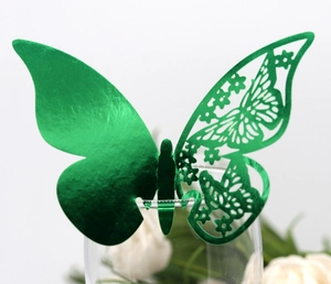 Detail of green metallic butterfly with laser-cut hollow pattern on glass rim