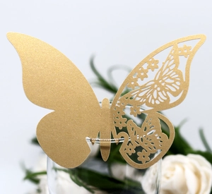 Macro shot of gold laser-cut butterfly place cards used for elegant glass rim decoration