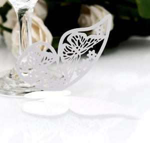 Macro view of white 3D laser-cut butterfly place card on a wine glass edge