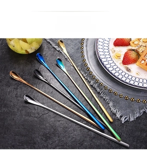 Six assorted long-handle stainless steel spoons on a grey stone textured background