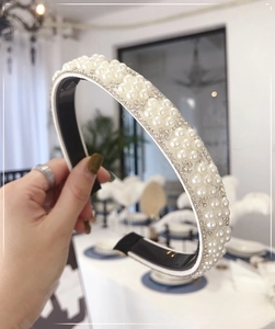 Close-up of elegant pearl headband featuring sparkling rhinestones and black leather lining