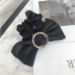 Detail of black satin scrunchie with sparkling rhinestone ring and elegant bow design