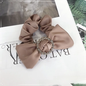 Detail of mocha brown satin scrunchie with a large bow and sparkling crystal center