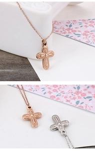 Detailed view of cross pendant necklaces in rose gold and silver on a floral card