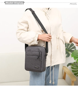 Detail of grey oxford cross-body bag featuring a metal logo and adjustable shoulder strap