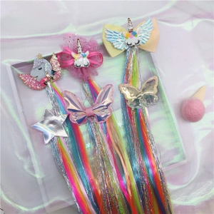 Detailed view of unicorn hair clips featuring rainbow hair extensions and glitter wings