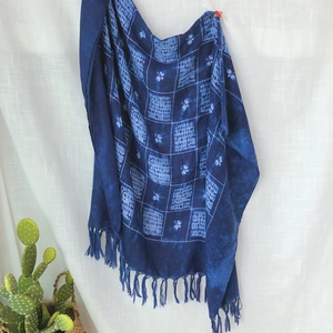 Detail of blue tie-dye plaid scarf with handmade knotted tassels and floral patterns