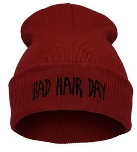 Dettaglio del berretto in maglia rosso scuro con scritta nera Bad Hair Day ricamata