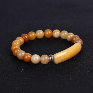 Macro shot of tiger eye stone bracelet featuring orange beads and a center bar element