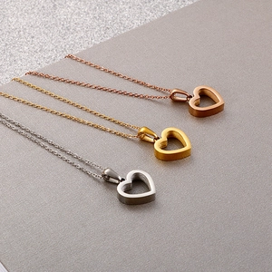 Tre collane con ciondolo a cuore in oro rosa, oro e argento su sfondo materico scuro