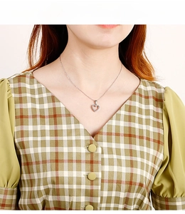 Minimalist silver heart-shaped pendant necklace worn by a model in a V-neck dress