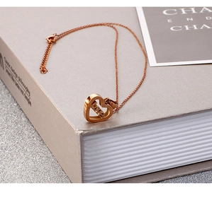 Détail du pendentif cœur en or rose avec gravure LOVE sur une chaîne à maillons