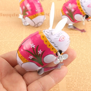 Close-up of retro clockwork tin rabbit toy with pink floral patterns on vintage background