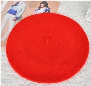 Detailed top view of red wool beret cap placed on magazine with lace background