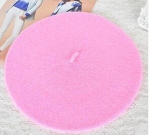 Detailed top view of a soft pink wool blend beret hat on a white lace fabric background