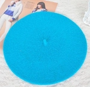 Flat lay of a sky blue wool beret hat on white lace background with a lifestyle touch