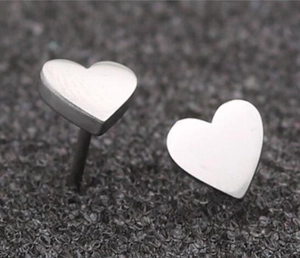 Macro shot of minimalist heart-shaped stainless steel stud earrings on black texture