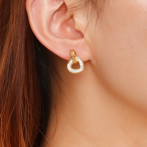 Elegant gold-plated heart stud earrings with sparkling pavé diamonds on model's ear