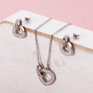 Silver double-heart necklace and earring set with diamond accents on pink background