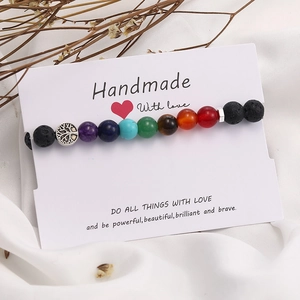 Detail of handmade chakra bead bracelet with lava stones and silver tree of life charm