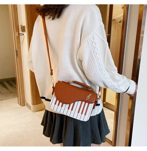 Creative piano keyboard crossbody bag worn with a white sweater and pleated skirt