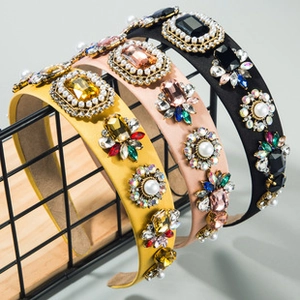 Detail of baroque headbands with sewn crystals and pearls on satin fabric texture
