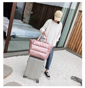 Pink quilted waterproof travel bag shown on a silver suitcase handle in an outdoor setting