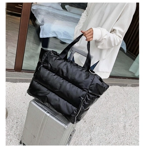 Quilted travel tote bag placed on silver suitcase handle for luggage attachment