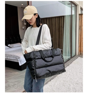 Detail view of black quilted tote bag with puffer padding and adjustable shoulder strap
