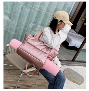 Pink quilted fitness bag with side compartment holding a matching yoga mat on a balcony